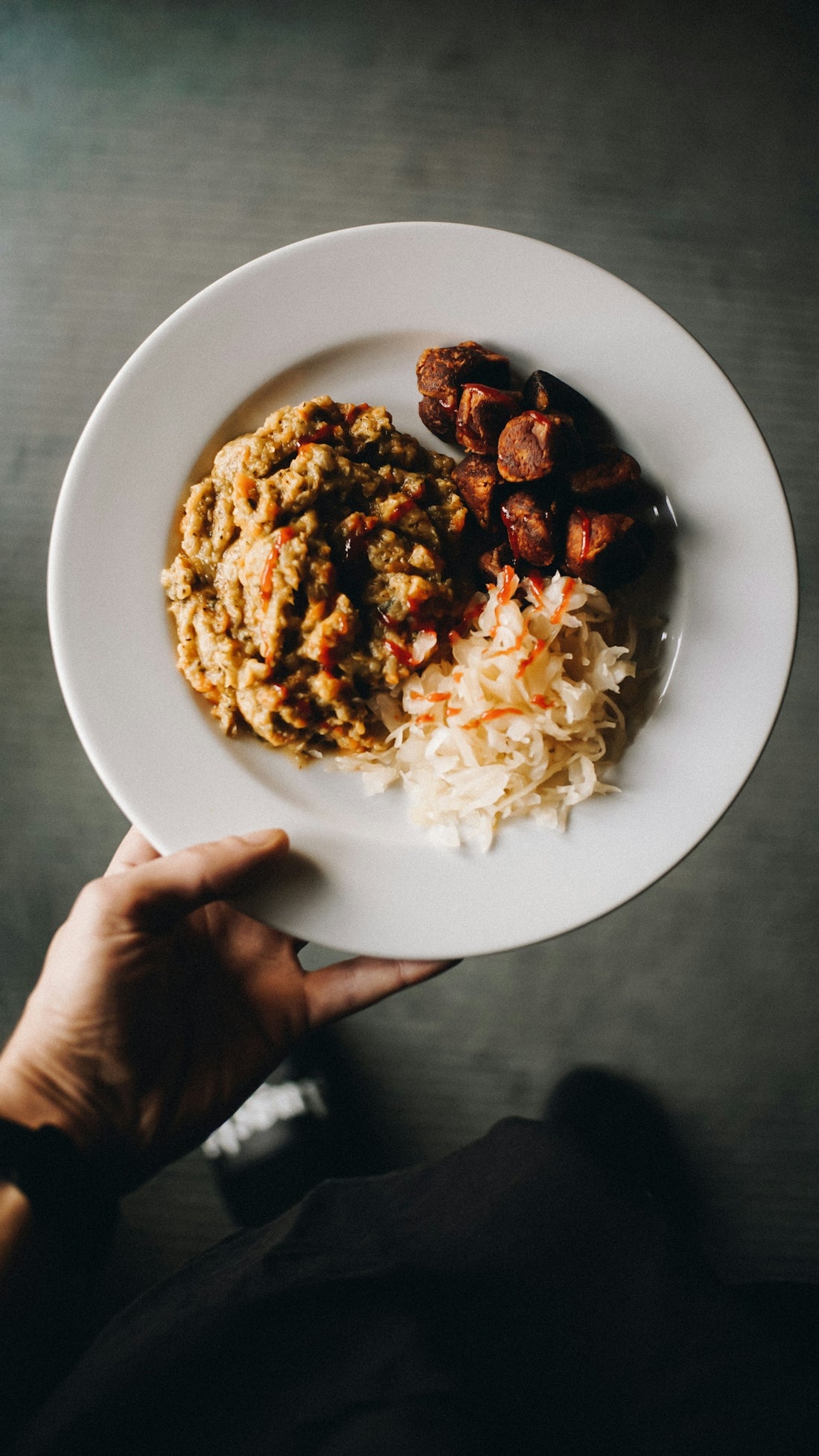 a person holding a plate of food on a table