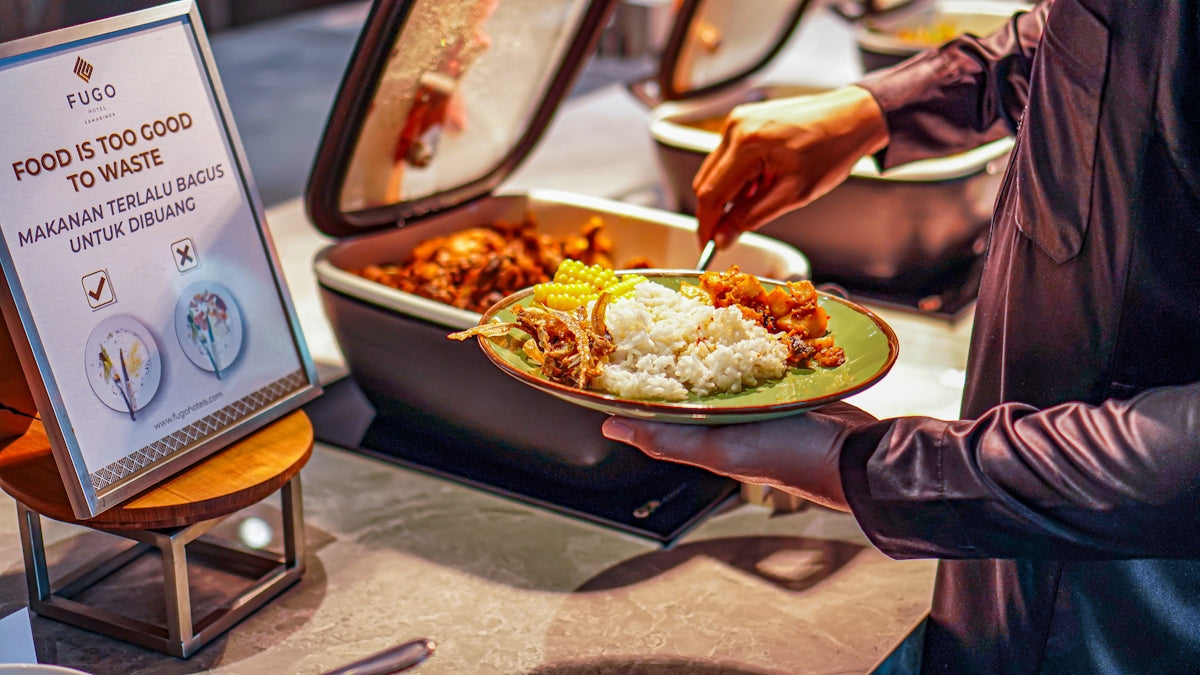 a person holding a plate of food in front of a sign