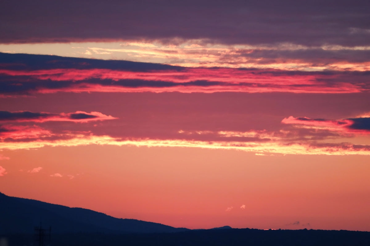 a plane flying in the sky at sunset