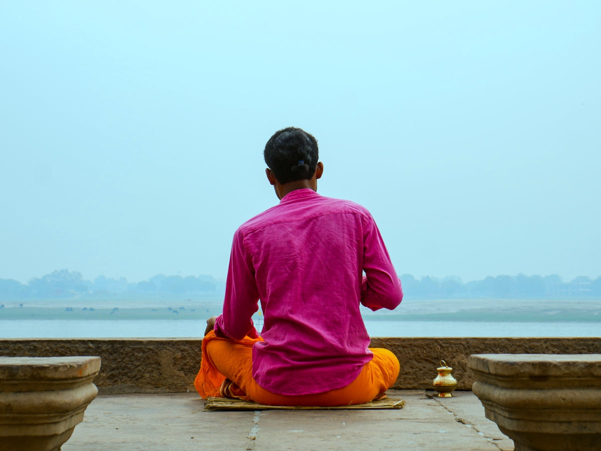 A man in a pink shirt sitting on a ledge