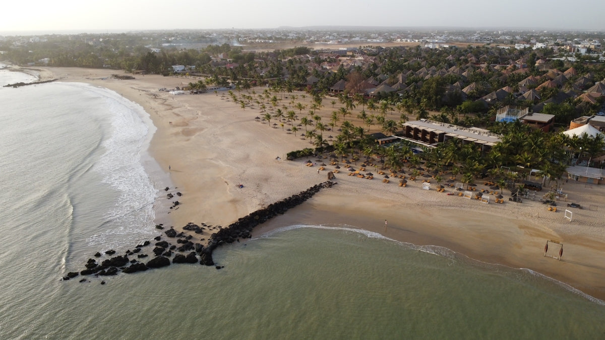 A scenic beach and shore with buildings and trees.