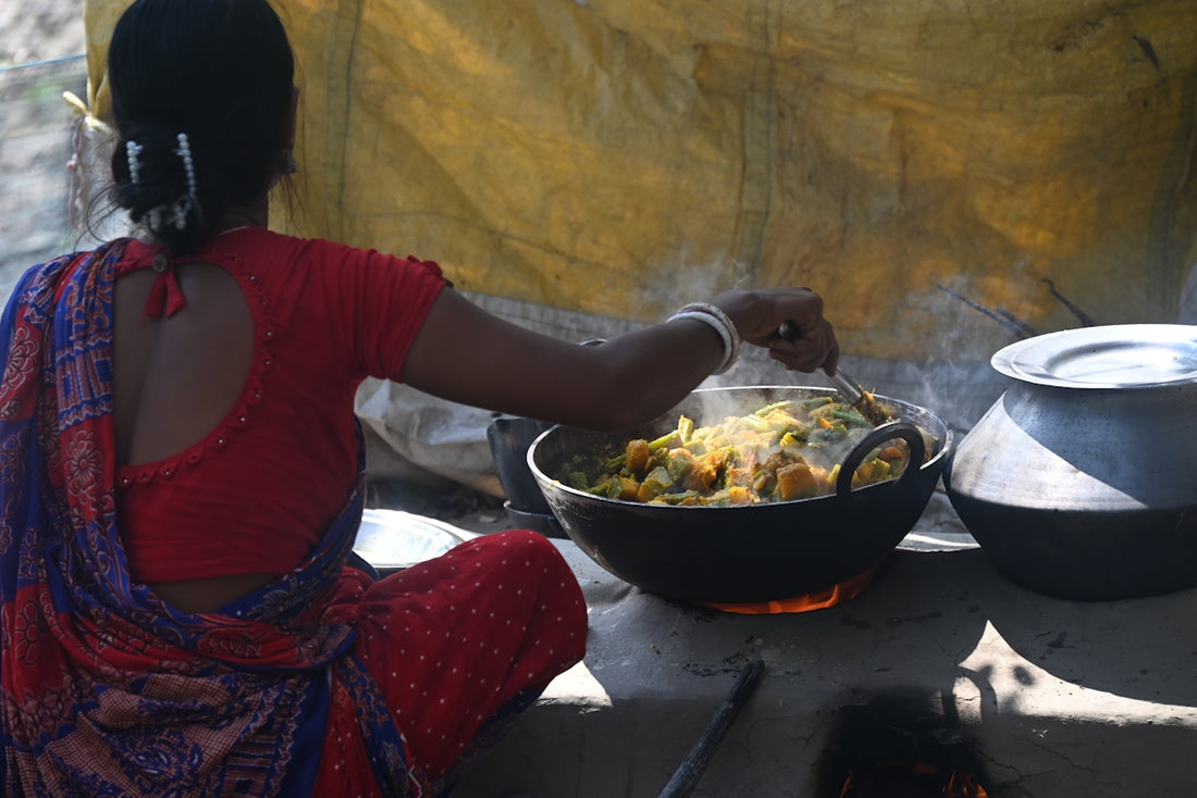 A woman is cooking food over a fire.