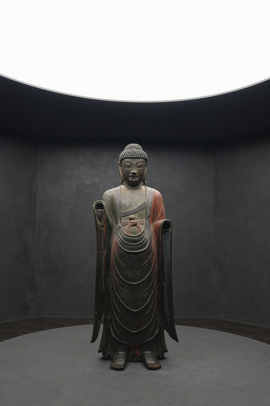 A buddha statue stands in a minimalist space.