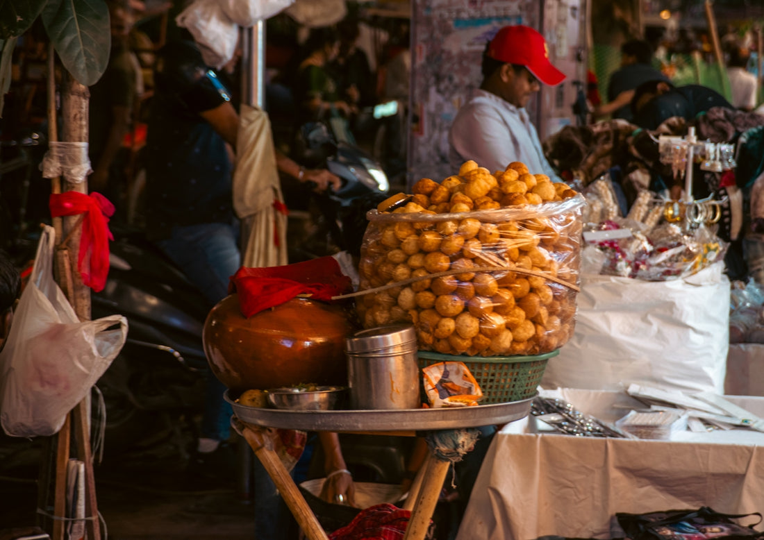 Street vendor selling snacks with large container of food.